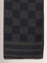 Close-up of a charcoal grey and black printed men’s muffler with Greek key geometric pattern and fringed edge.
