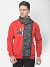 Man wearing a charcoal grey and black printed muffler with a red sweatshirt.