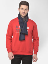 Man wearing a navy and brown striped muffler with a red sweatshirt.