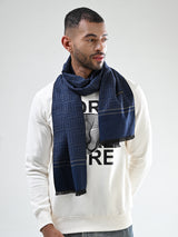 Man wearing a navy blue and grey printed men’s muffler with Greek key geometric pattern and fringed edges.