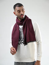 Man wearing a burgundy and grey printed men’s muffler with small square motif pattern.