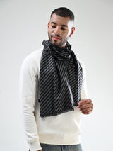 Man wearing a black and grey striped men’s muffler with chevron pattern and fringed edges.
