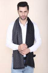 Man wearing a black and grey printed men’s muffler with small square motif pattern.